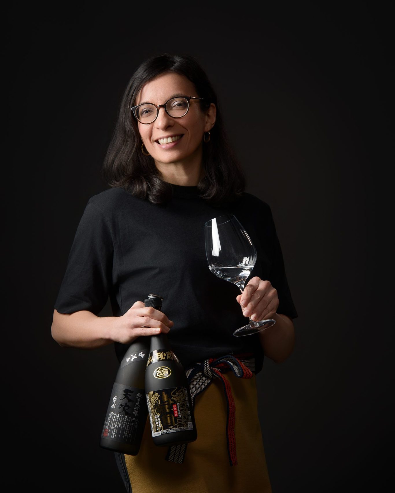 Karen Esteves Ribeiro, sommelière de saké, arbore un sourire, vêtue de son maekake japonais